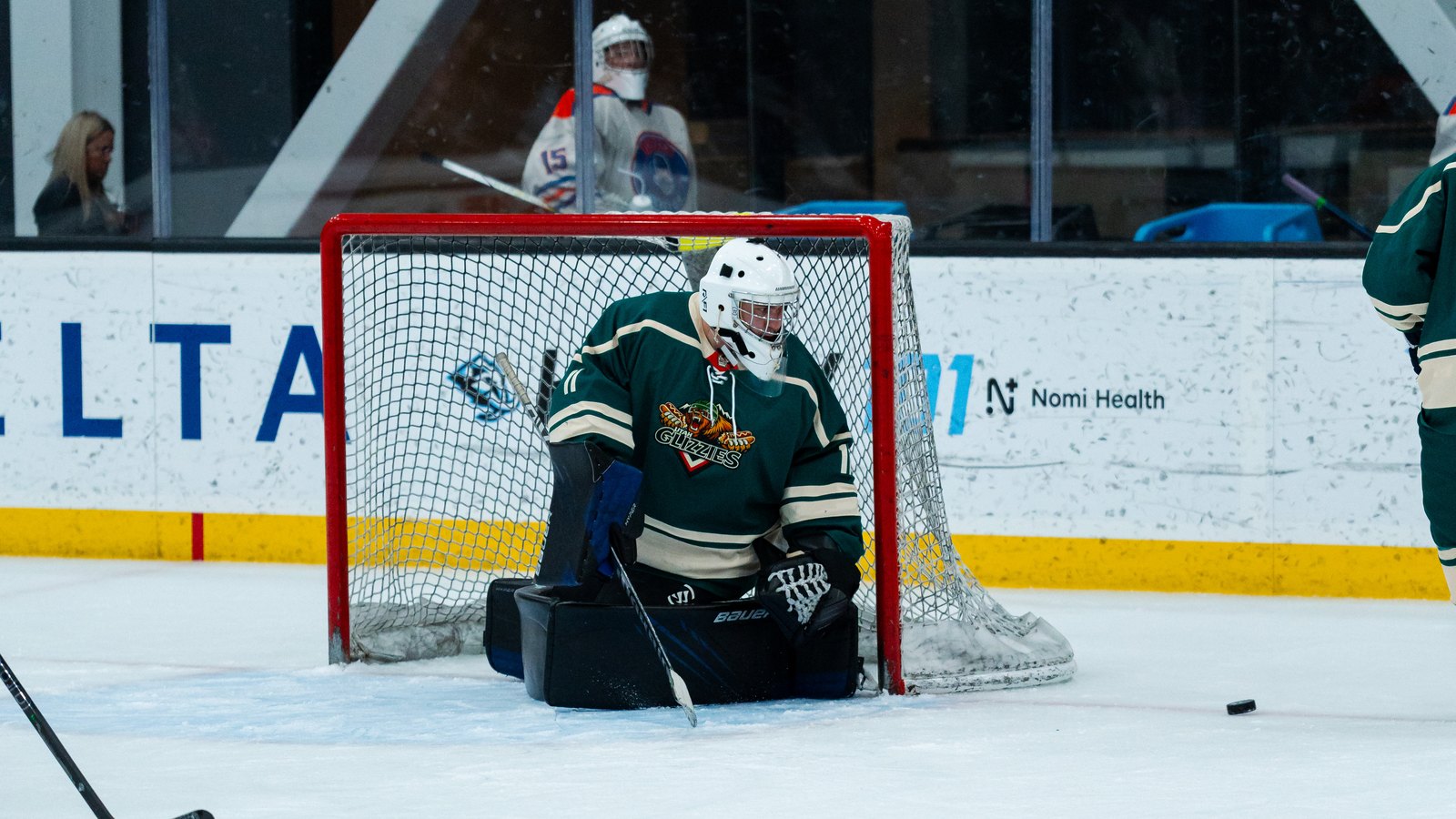 Adult rec hockey player's skates digging into the ice in front of the net